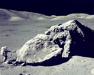 Schmidt on the moon next to a very large rock